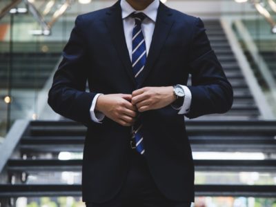 A person standing near the stairs buttoning up a suit jacket.