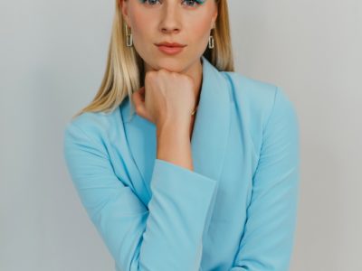 emma oleck sitting in a blue blazer with her legs crossed